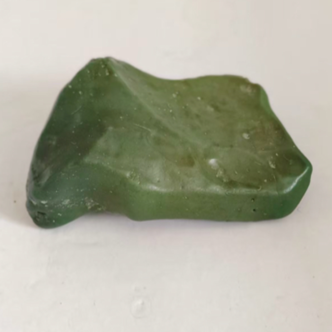 阿拉善彩玉原石，草绿色泽，油润细腻，表面光滑有自然纹路。纯天然