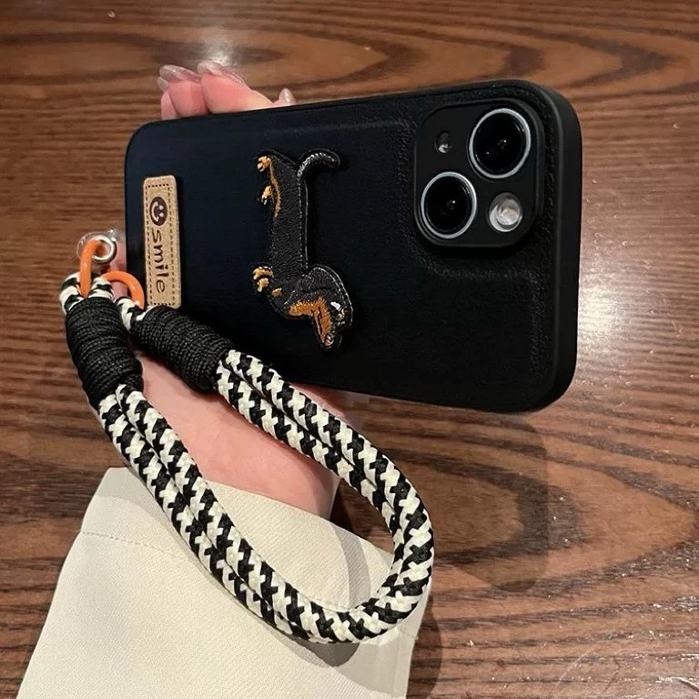 适用于苹果16pro手机壳15素皮纹黑色腊肠狗笑脸标签手提绳14高级